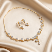 Gold necklace and earrings set on a beige fabric background