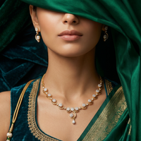 Woman wearing a gold necklace and earrings with a green saree