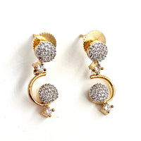 Gold and silver earrings with spherical designs on a white background