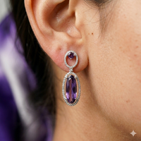 Close-up of an ear wearing a purple gemstone earring with a blurred background