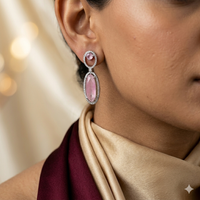 Close-up of a person wearing a pink gemstone earring with a blurred background