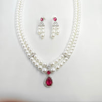 Pearl necklace with red gemstones and matching earrings on a white background
