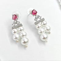 Pearl earrings with pink gemstones and silver accents on a white background