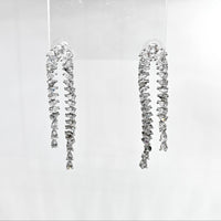Pair of dangling diamond earrings on a clear background