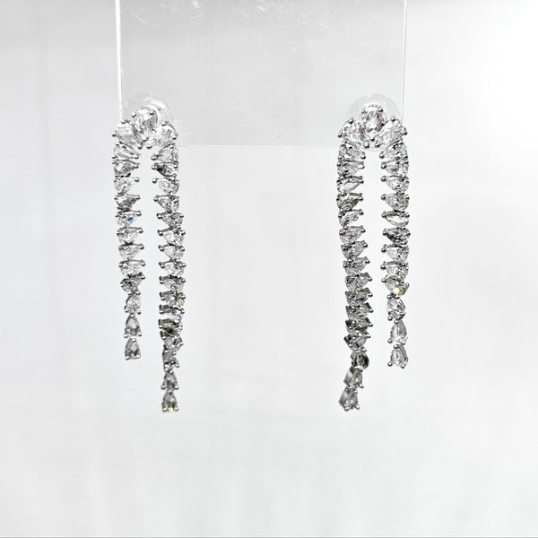Pair of dangling diamond earrings on a clear background