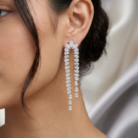 Close-up of a woman wearing a sparkling earring with a neutral background