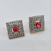 Pair of square-shaped earrings with red gemstones and gold accents on a light gray background