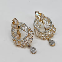 Pair of gold and crystal earrings on a light gray background