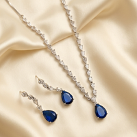 Jewelry set with blue teardrop earrings and necklace on beige fabric