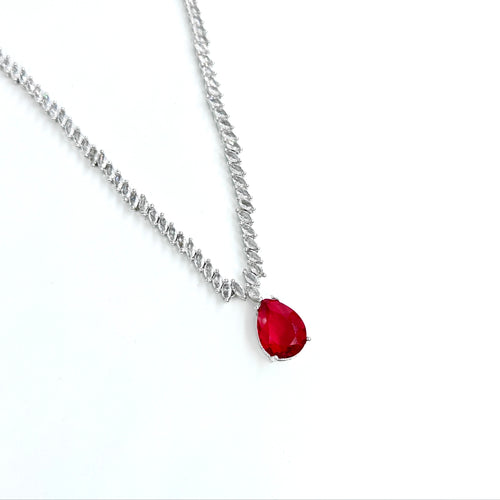 Silver necklace with a red gemstone pendant on a white background