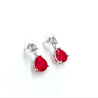 Pair of earrings with red teardrop-shaped gemstones on a white background