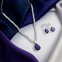 Jewelry set with necklace and earrings featuring purple stones on a satin surface
