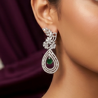 Elegant earring with a green gemstone worn by a person against a dark background