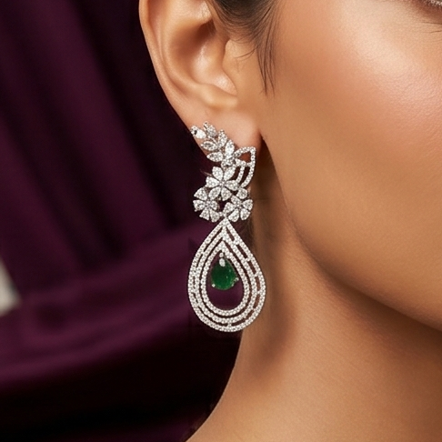 Elegant earring with a green gemstone worn by a person against a dark background