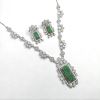 Jewelry set with necklace and earrings featuring green stones on a white background