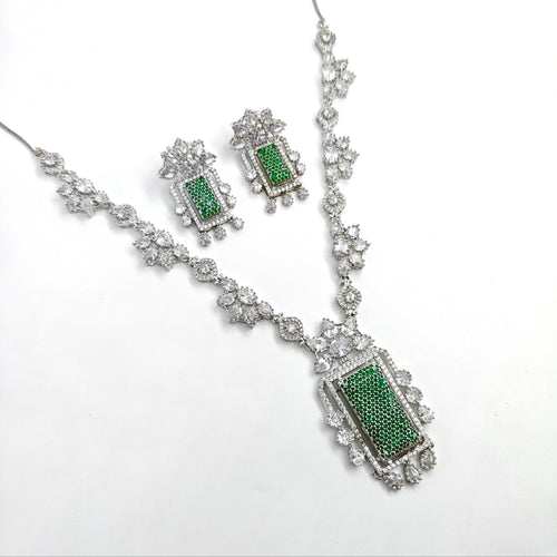 Jewelry set with necklace and earrings featuring green stones on a white background
