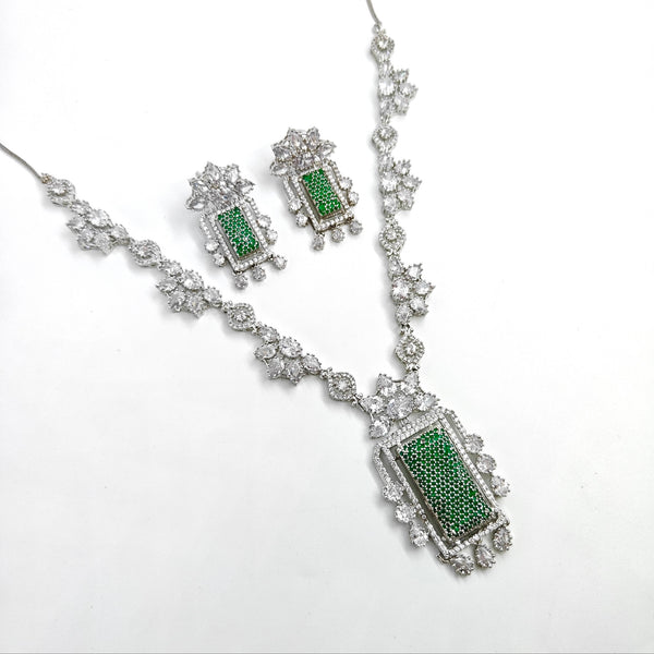 Jewelry set with necklace and earrings featuring green stones on a white background