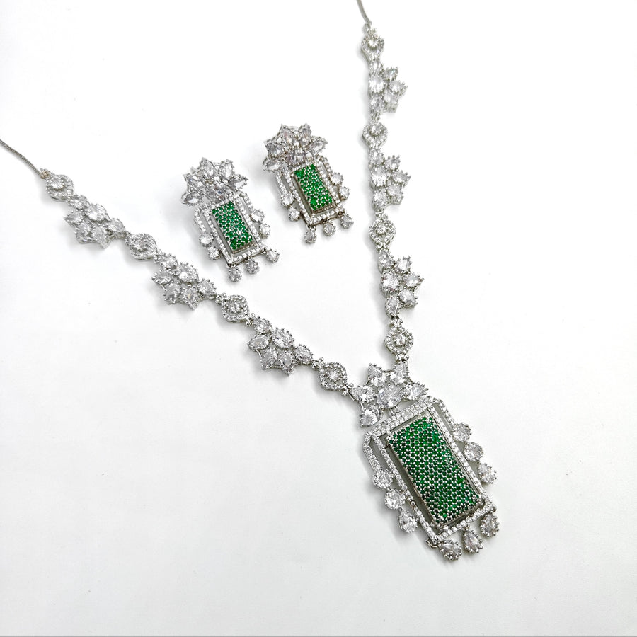 Jewelry set with necklace and earrings featuring green stones on a white background
