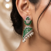 Close-up of a woman wearing green and white gemstone earrings with a blurred background