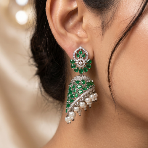 Close-up of a woman wearing green and white gemstone earrings with a blurred background