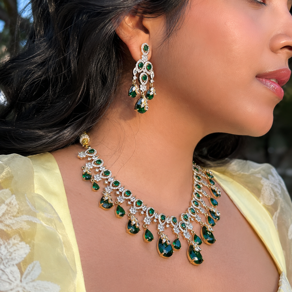 Close-up of a woman wearing a green and gold necklace and earrings.