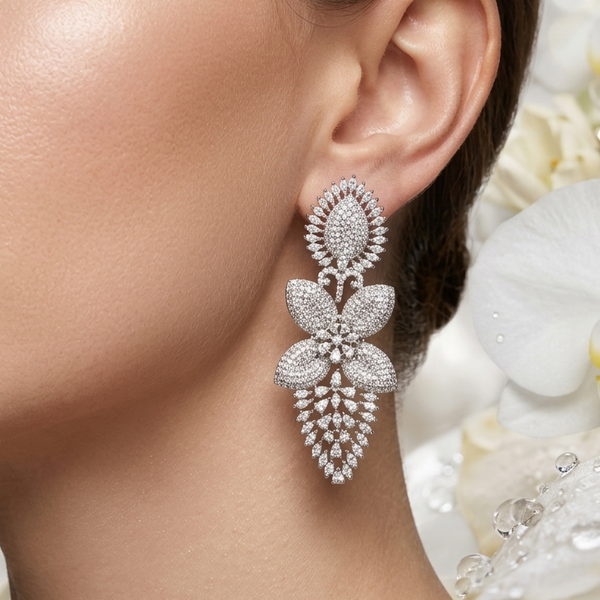 Close-up of a woman's ear wearing a sparkling earring with a blurred floral background