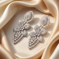 Pair of silver leaf-shaped earrings on beige fabric