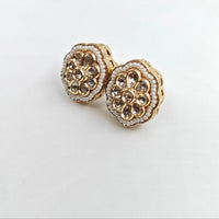 Gold floral earrings with gemstones on a light gray background