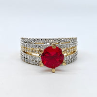 Ring with a red gemstone and diamond-studded band on a white background