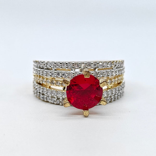 Ring with a red gemstone and diamond-studded band on a white background