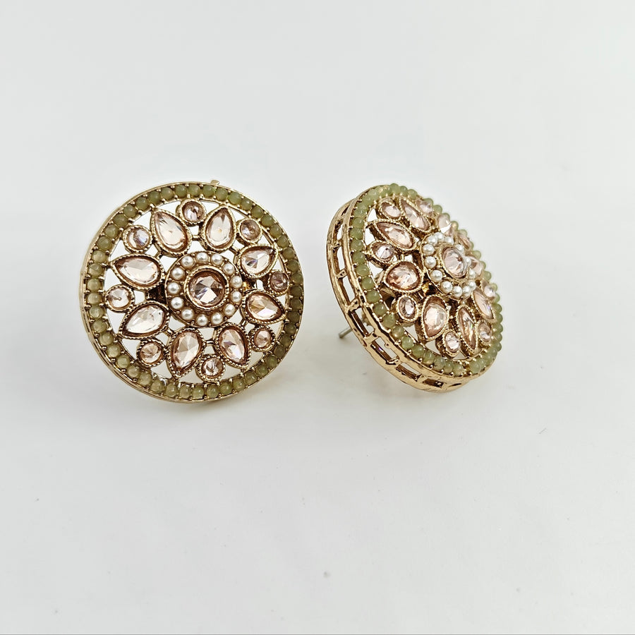 Gold round earrings with gemstone-like embellishments on a light gray background