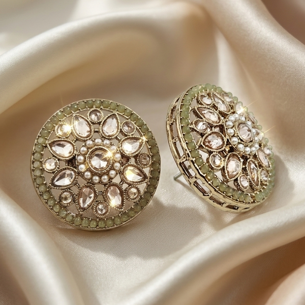 Decorative round earrings with gemstones on a beige satin background