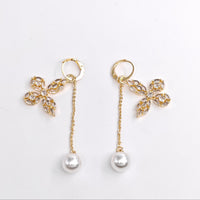 Gold earrings with floral designs and pearl drops on a white background