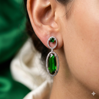 Close-up of a person wearing green gemstone earrings with a blurred background