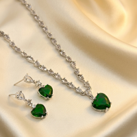 Jewelry set with heart-shaped green gemstones on a satin surface
