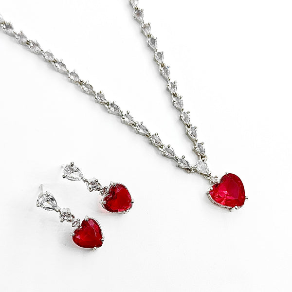 Jewelry set with red heart-shaped pendants on a white background