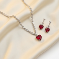 Jewelry set with red heart-shaped gemstones on a beige fabric background