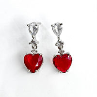 Heart-shaped red earrings with clear gemstones on a white background