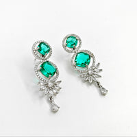 Pair of earrings with green gemstones and silver accents on a white background