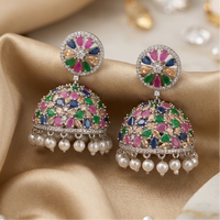 Colorful gemstone earrings with pearl accents on a soft fabric background