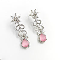 Earrings with pink teardrop stones and silver floral designs on a white background