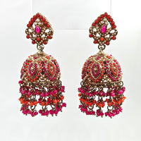 Pair of ornate earrings with pink and red stones on a white background