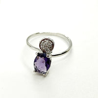 Silver ring with a purple gemstone on a white background