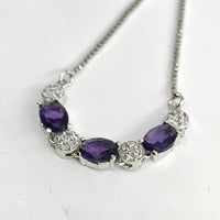 Necklace with purple gemstones and silver chain on a white background