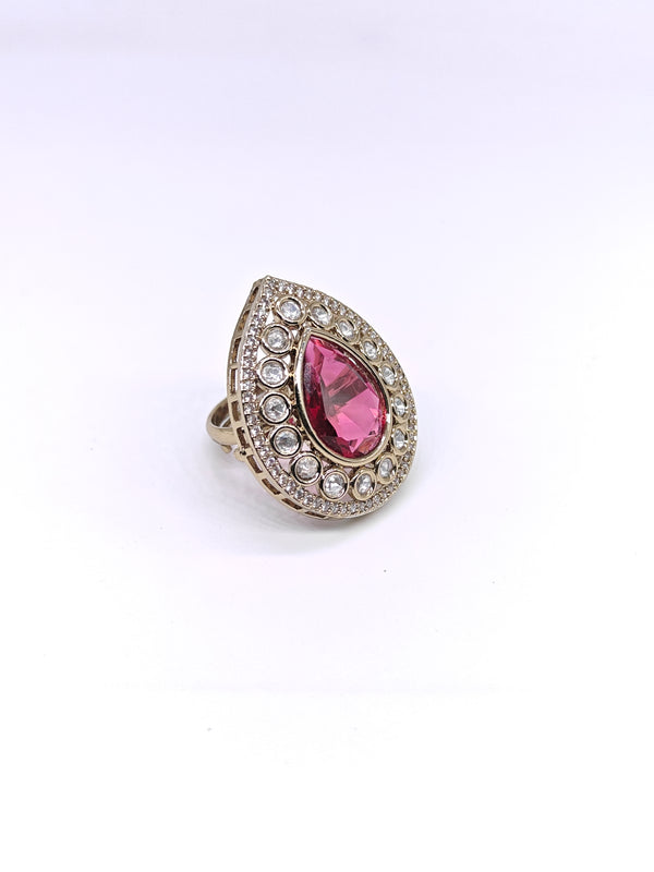 Ring with a pink teardrop-shaped gemstone and diamond-studded band on a white background