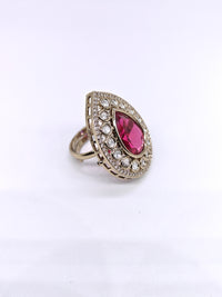 Ring with a pink gemstone and diamond-studded band on a white background