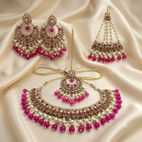 Ornate jewelry set with pink and white beads on a satin background