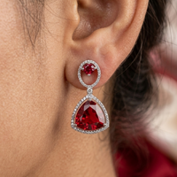 Close-up of a red gemstone earring worn on an ear with a blurred background