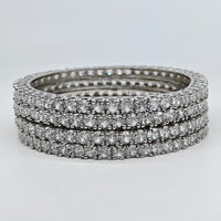 Stack of diamond eternity rings on a light gray background