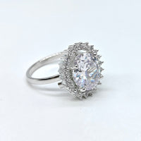 Silver ring with a large central gemstone and smaller stones on a white background